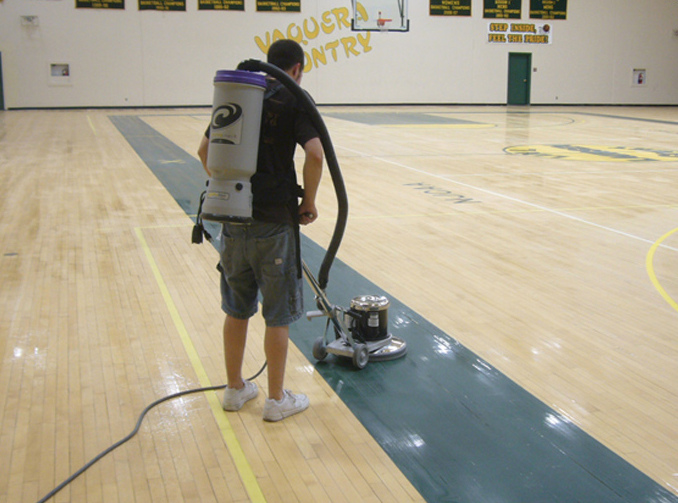 man operating a floor cleaning machine on a high school basketball court